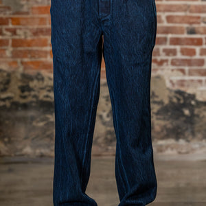 A person wearing the 3sixteen Easy Pant - Indigo Kendo Cloth n front of a rustic brick wall.