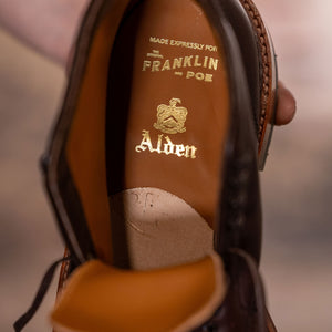 Brown leather cap toe boots closeup on Alden and Franklin and Poe branding on tan leather insole