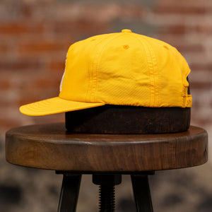 Franklin & Poe Surf Cap - Nylon Gold on stool, facing the side.