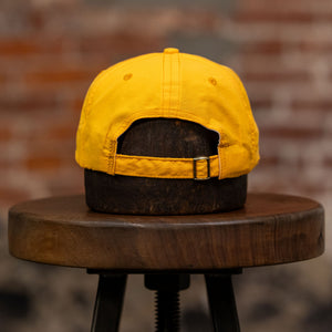 Franklin & Poe Surf Cap - Nylon Gold on stool, facing away from the camera. Showing adjustable strap. 
