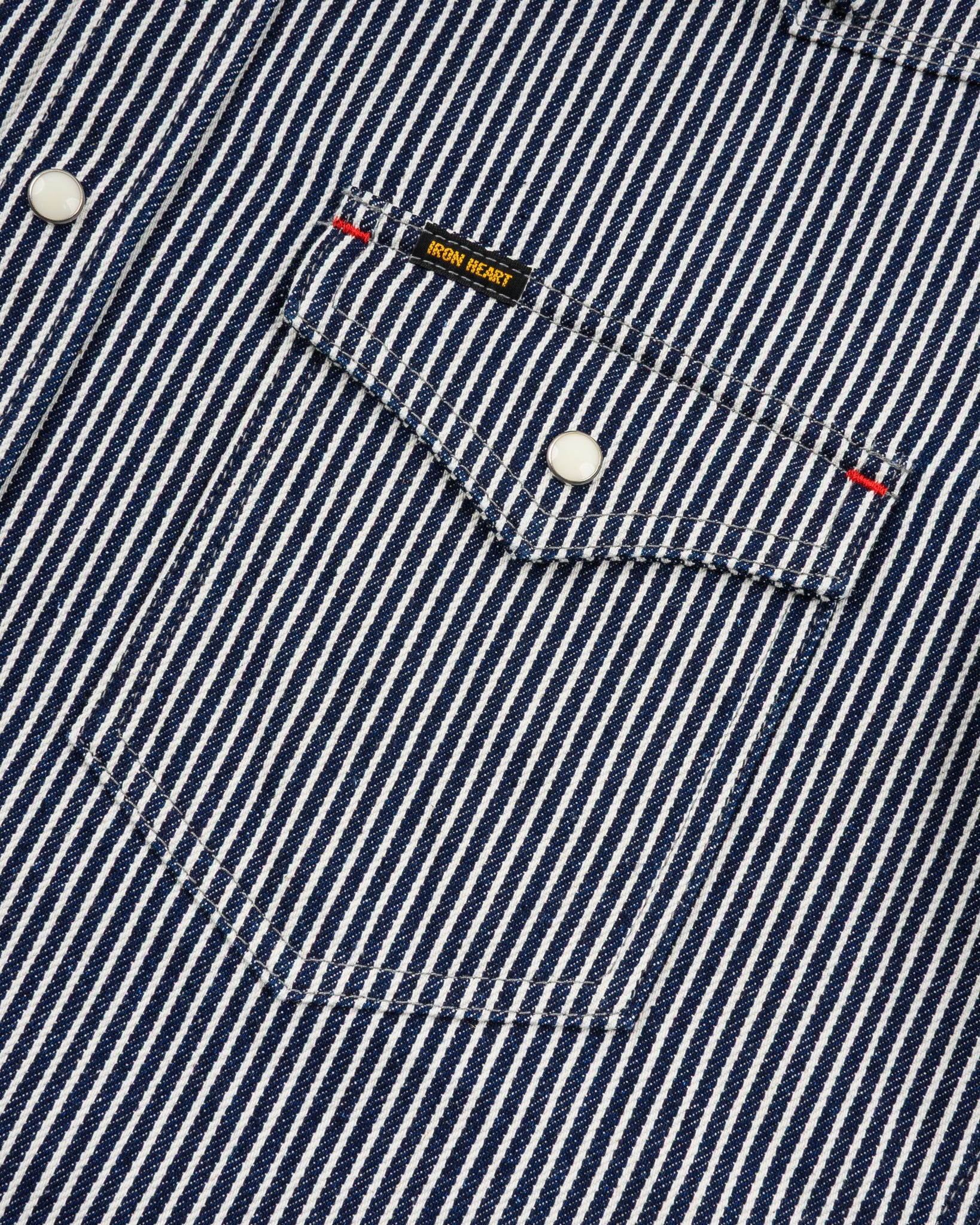 Western style shirt with indigo and white thin vertical stripes and white snaps close-up on pocket