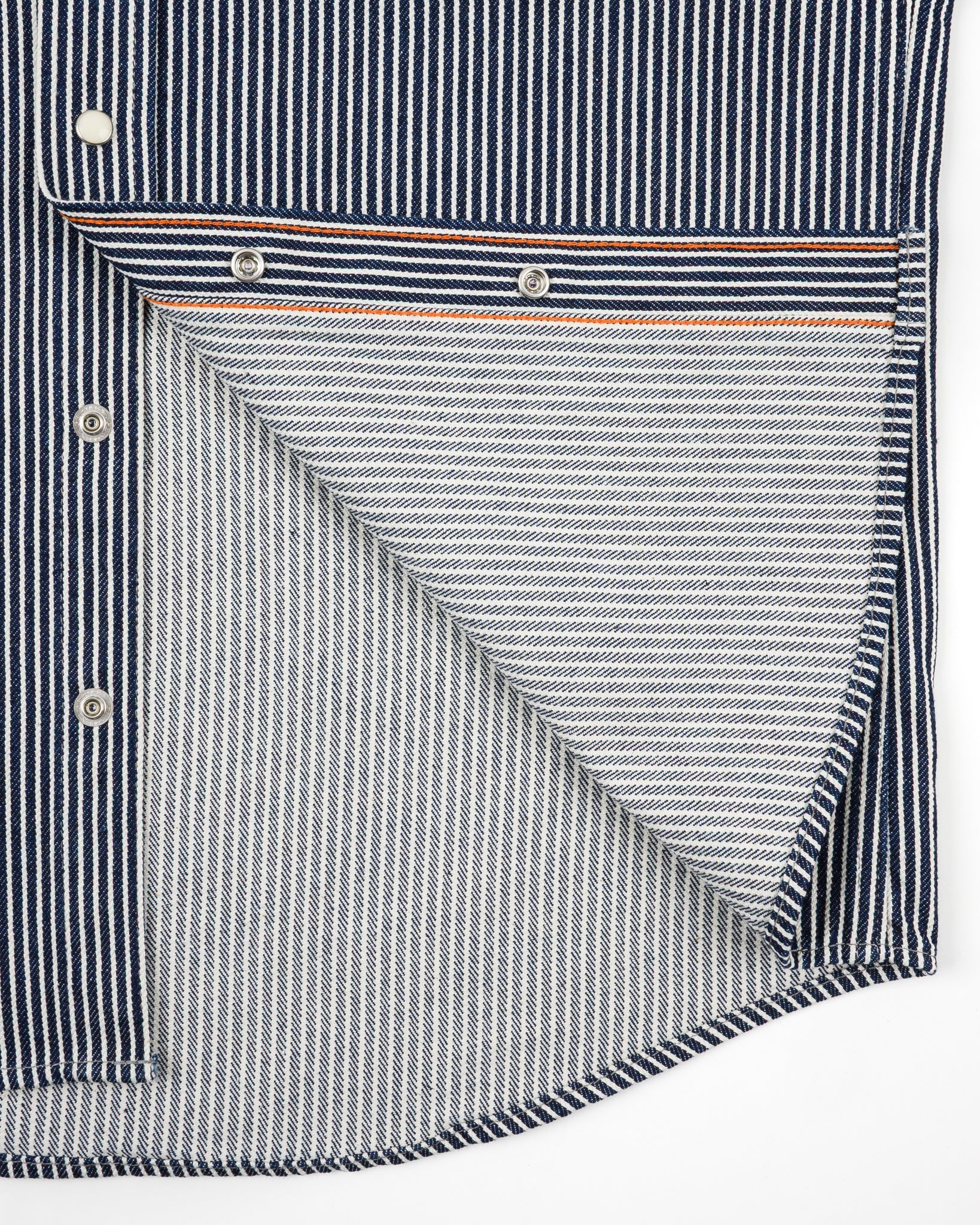 Western style shirt with indigo and white thin vertical stripes and white snaps close-up on snaps and both sides of fabric