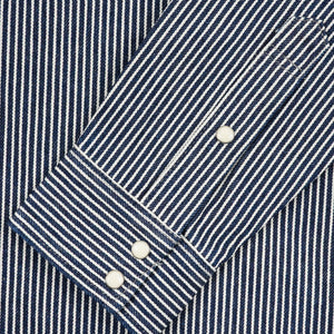 Western style shirt with indigo and white thin vertical stripes and white snaps close-up on sleeve buttoned