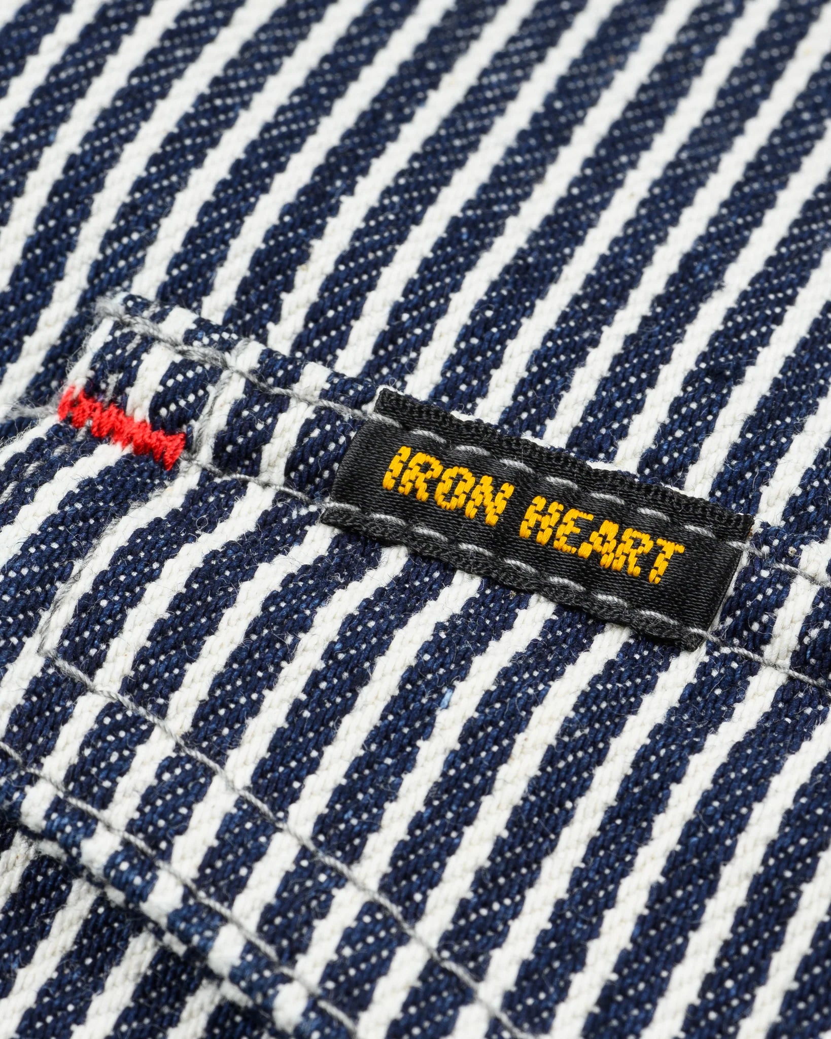 Western style shirt with indigo and white thin vertical stripes close-up on Black and Yellow Iron Heart logo on pocket