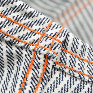 Western style shirt with indigo and white thin vertical stripes close-up on underside of fabric and orange bottom stitch 