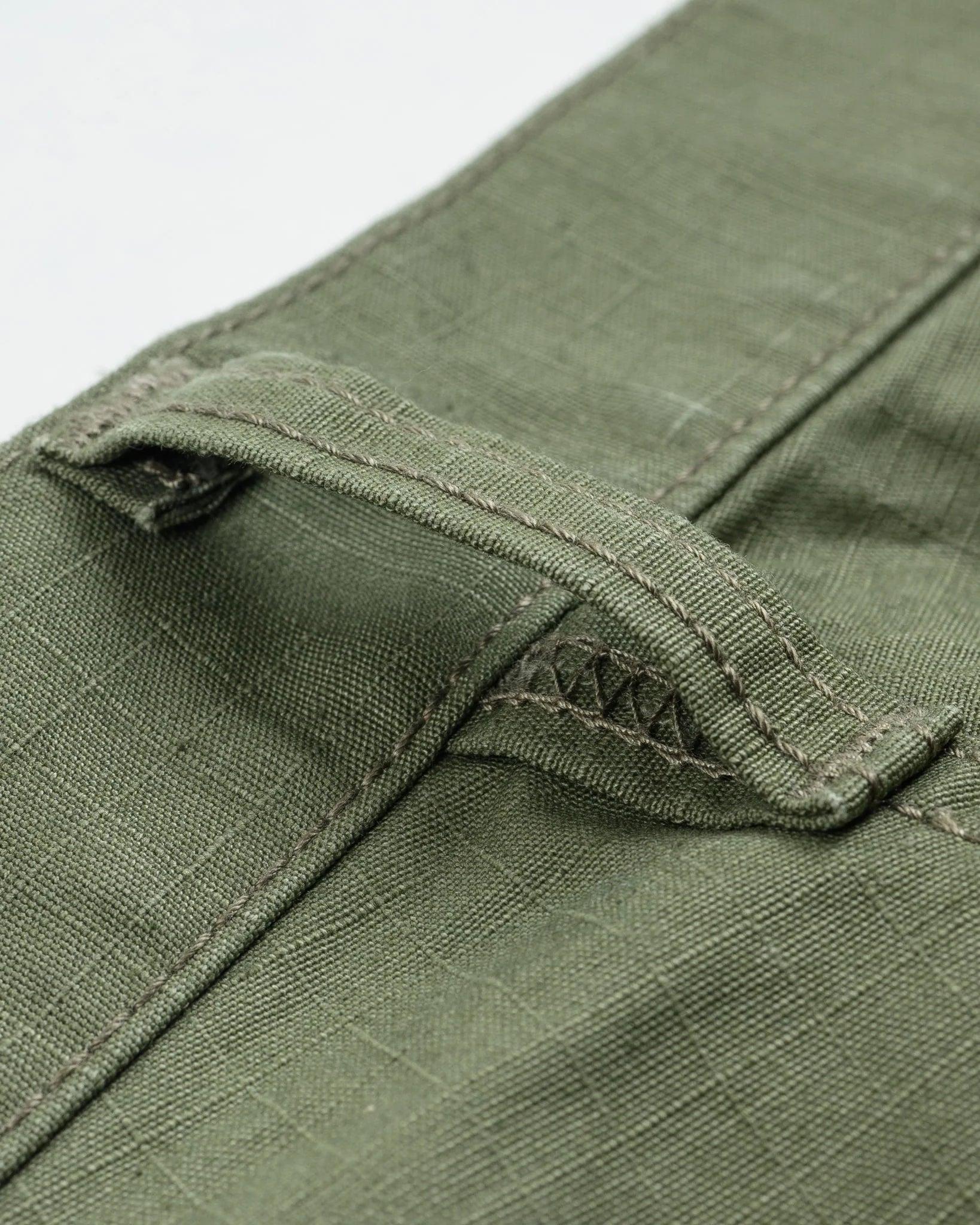 Olive pants laying flat closeup on belt loop