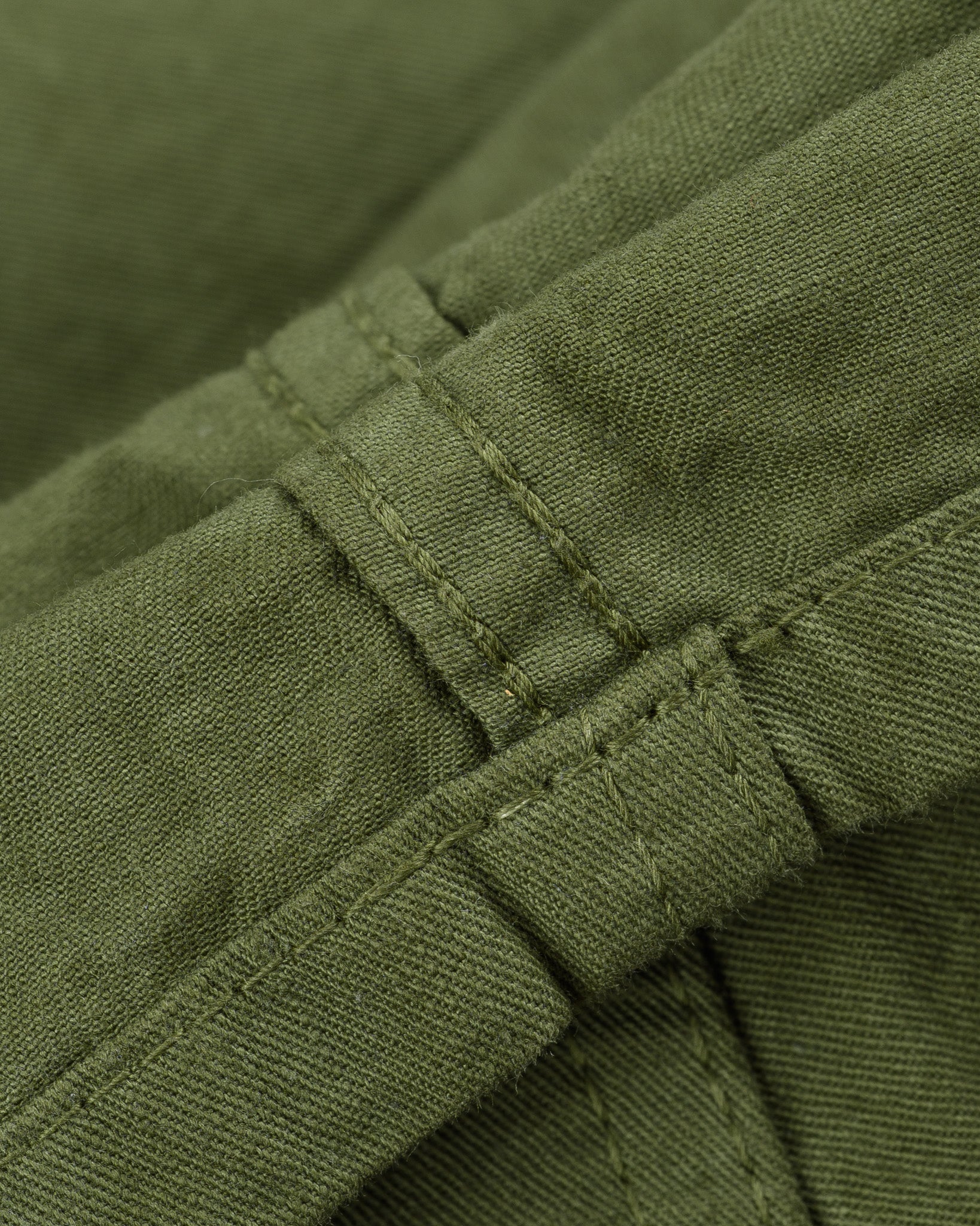 Olive mid length shorts laying flat closeup on stitching
