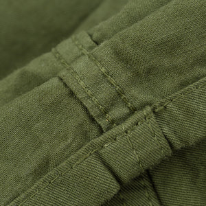 Olive mid length shorts laying flat closeup on stitching