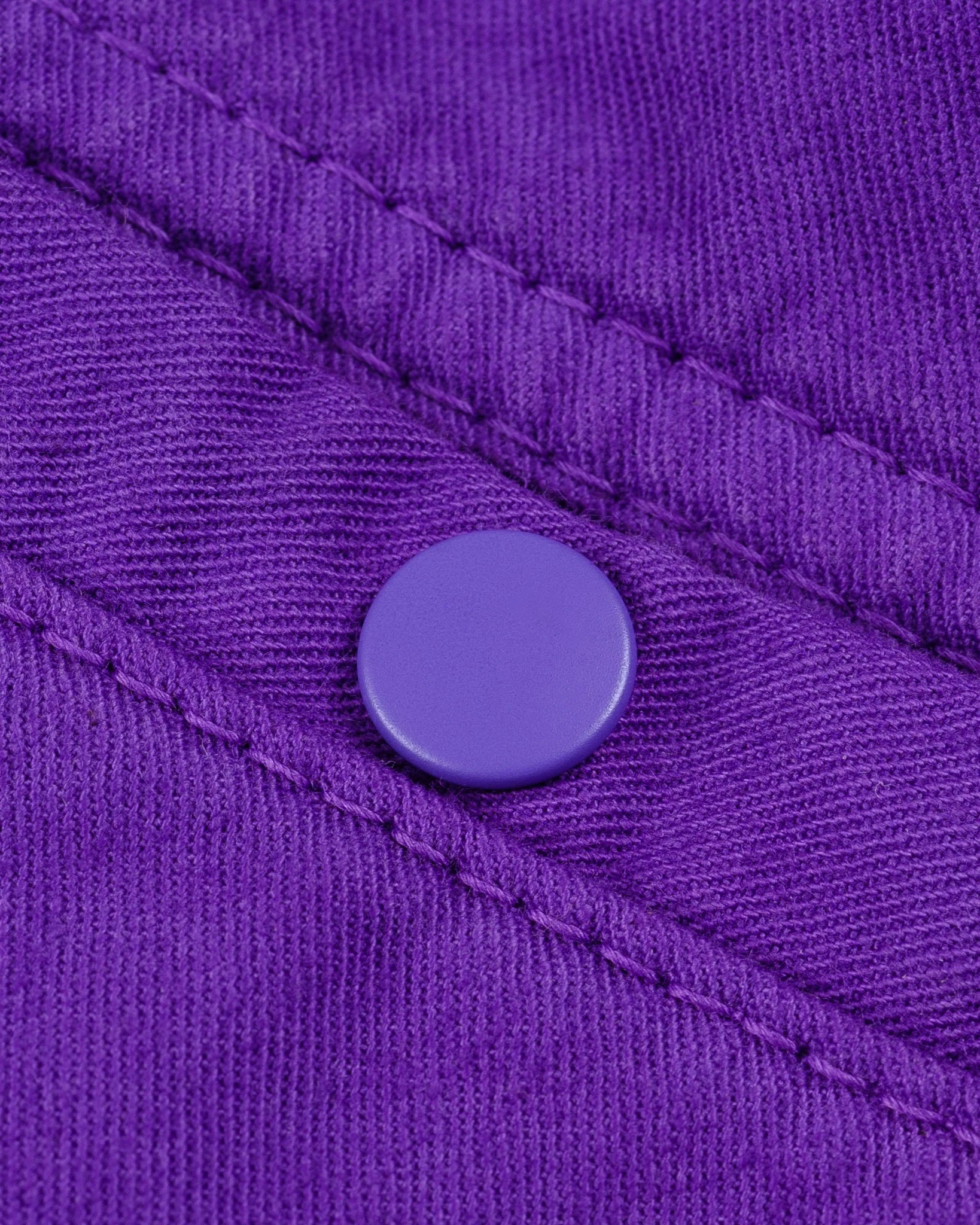 Purple mid length shorts back view laying flat closeup on snap pocket