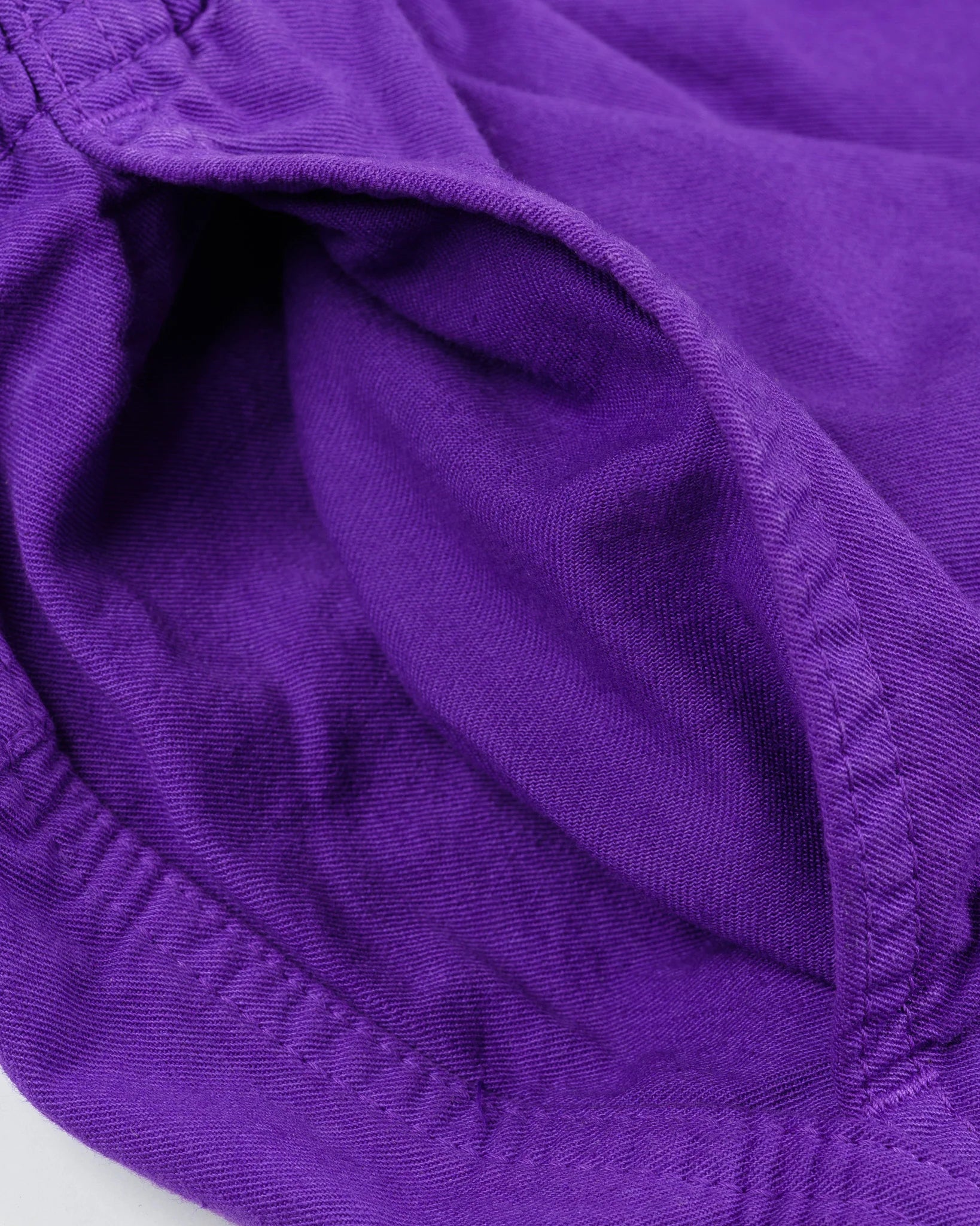 Purple mid length shorts laying flat closeup on side pocket