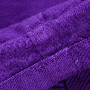 Purple mid length shorts laying flat closeup on stitching