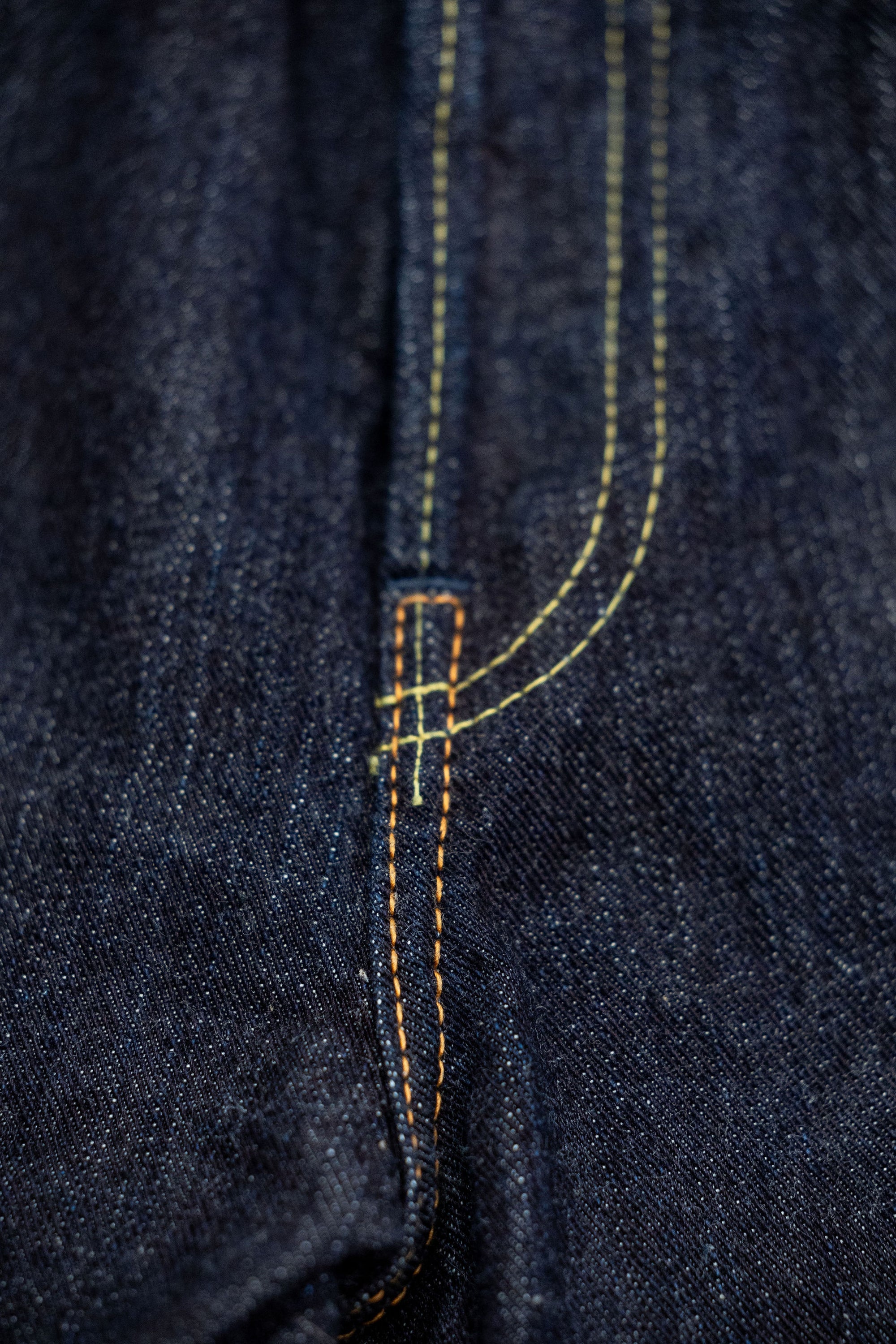 Indigo denim jeans wide cut front view laying flat close up on fly stitching
