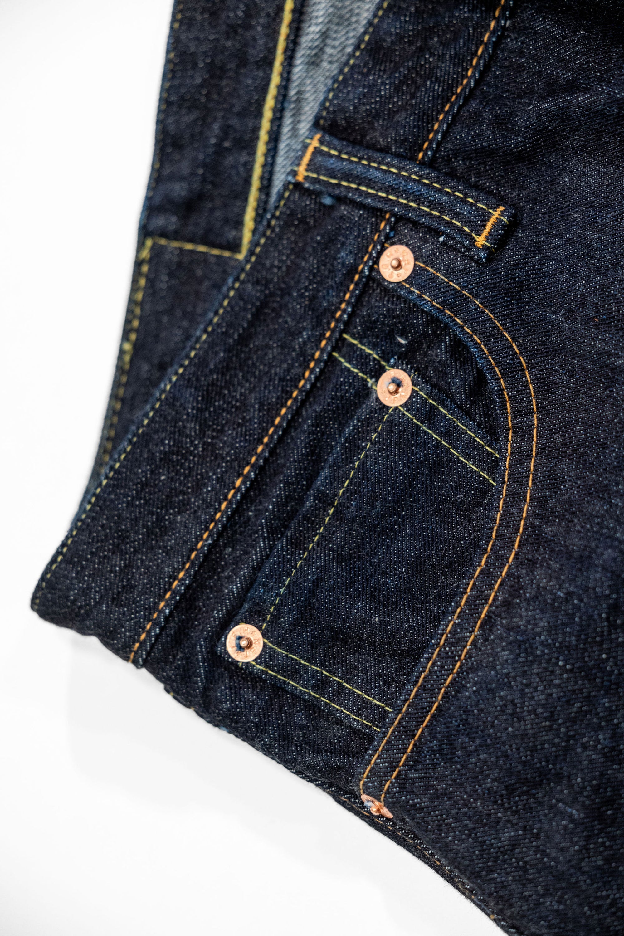 Indigo denim jeans wide cut front view laying flat closeup on front pocket