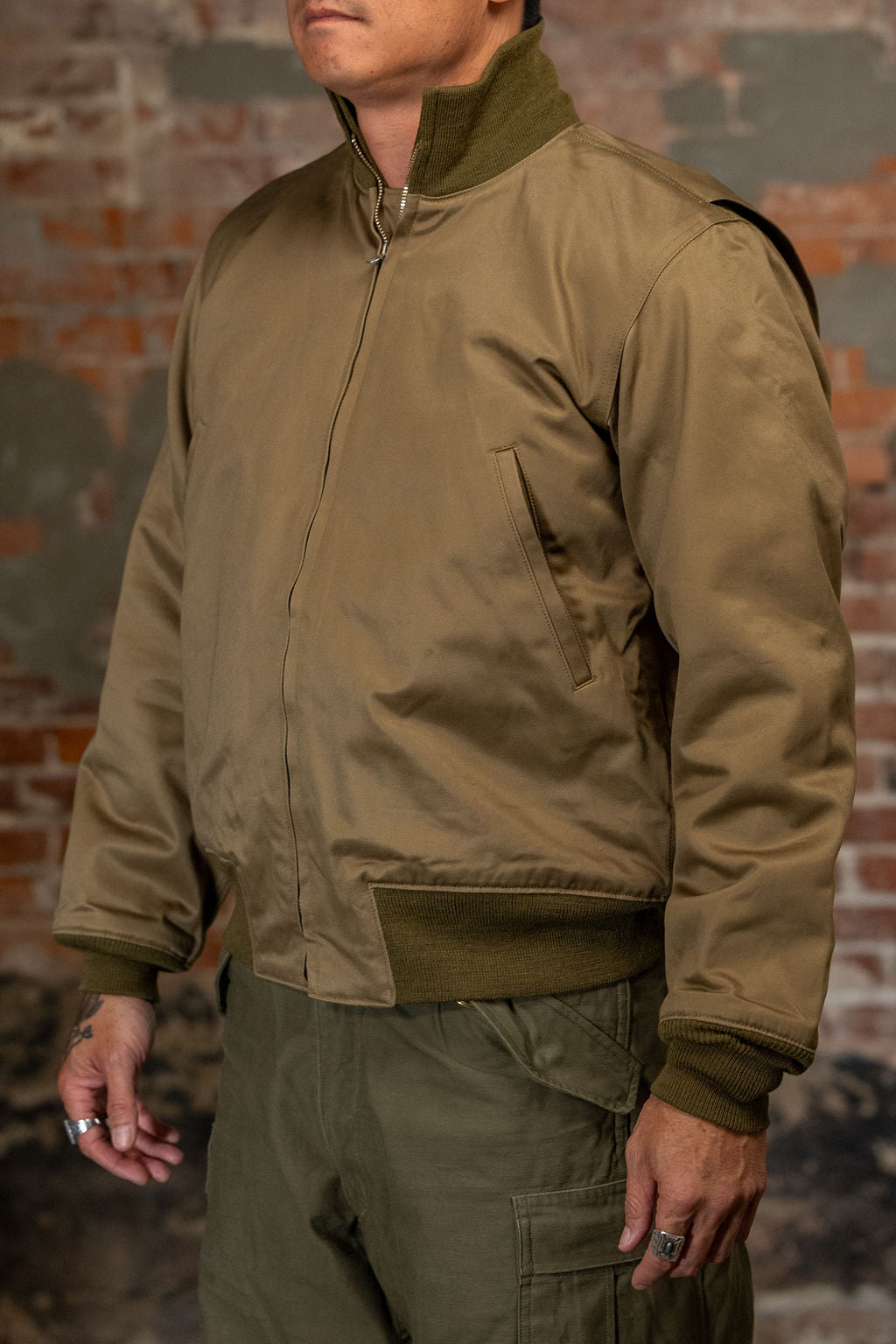 A man viewed from the side, wearing the  Buzz Rickson's BR15755 Type Tankers Slash Pocket “Buzz Rickson MFG. Co." in Light Olive Drab, viewed from the rear
