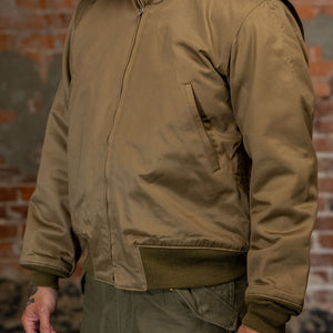 A man viewed from the side, wearing the  Buzz Rickson's BR15755 Type Tankers Slash Pocket “Buzz Rickson MFG. Co." in Light Olive Drab, viewed from the rear