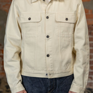 A person viewed from the front is wearing the  3sixteen Trucker Jacket - Buttermilk Twill which is a light cream canvas utility jacket 