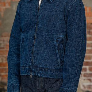 A person viewed from the back wearing 
the 3sixteen Club Jacket - Indigo Kendo Cloth, standing against a rustic brick wall.