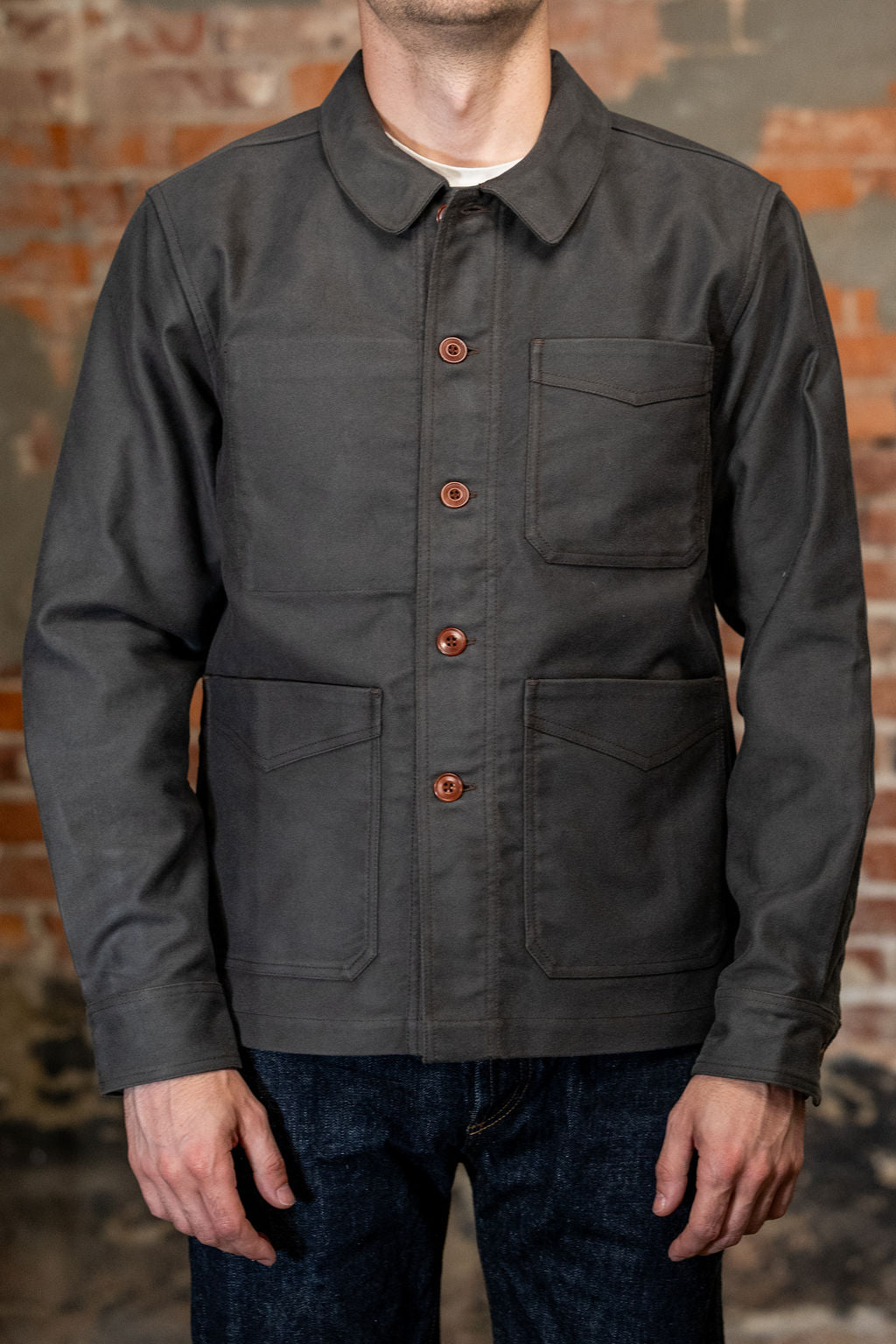 A man viewed from the front wearing
3sixteen French Work Jacket - Grey Moleskin, a dark charcoal gray long-sleeve button-up shirt 