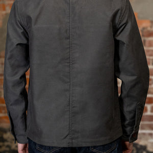 A man viewed from the back wearing
3sixteen French Work Jacket - Grey Moleskin, a dark charcoal gray long-sleeve button-up shirt 