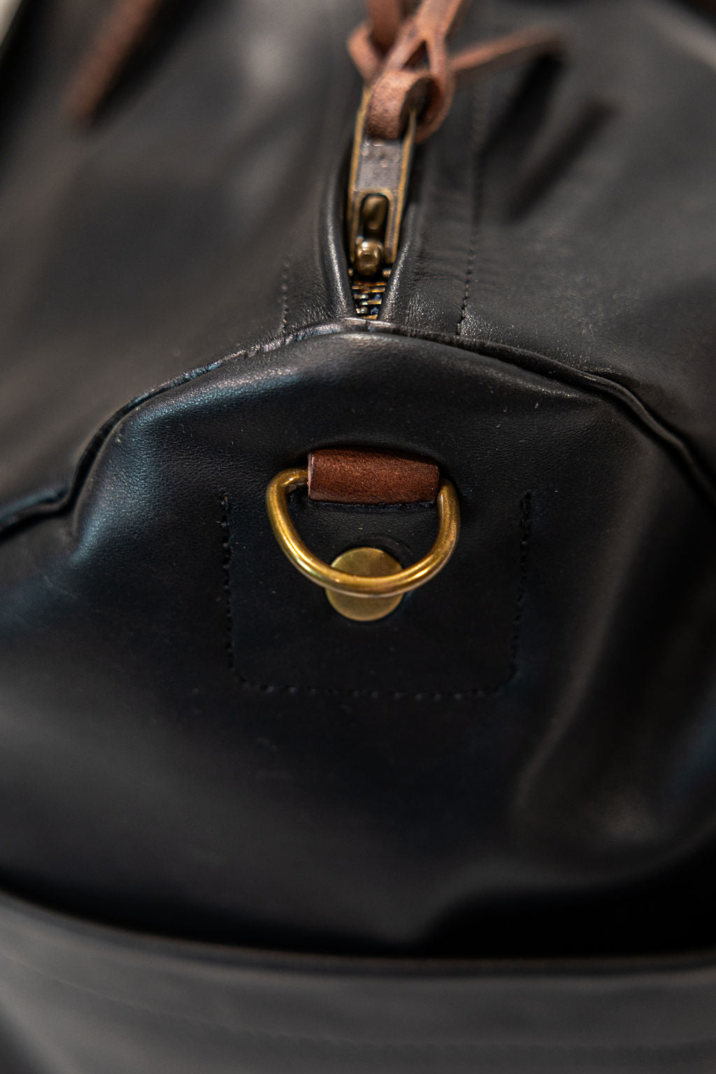 Black leather duffel bag with pockets and brown leather handles side view closeup
