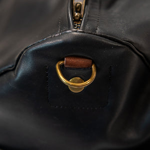 Black leather duffel bag with pockets and brown leather handles side view closeup