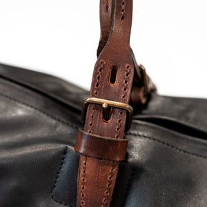 Black duffel bag with brown handles closeup on handle buckle