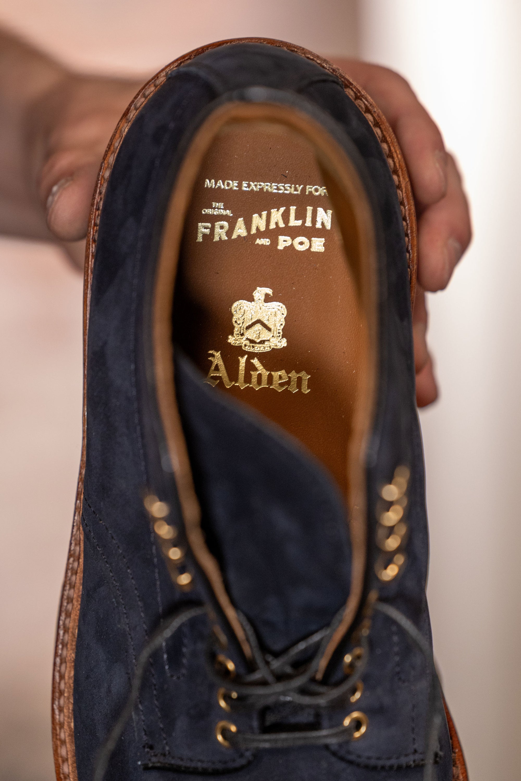 Navy blue suede cap toe boots close up on Alden and Franklin and Poe print on tan leather insole