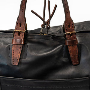 Black duffel bag with brown handles closeup on side