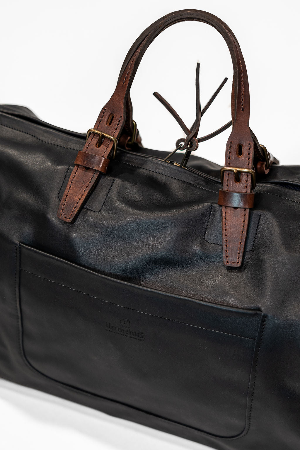 Black leather duffel bag with pockets and brown leather handles front view closeup