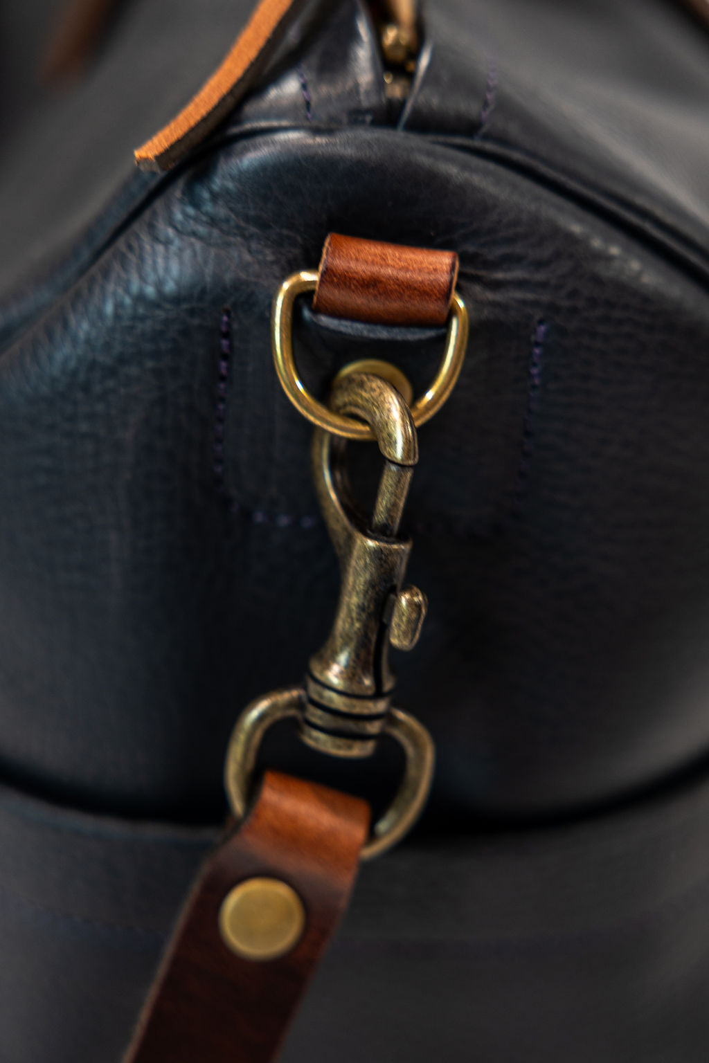 Black leather duffel bag with pockets and brown leather handles closeup on strap trigger hook