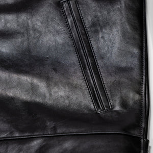 Black leather jacket laid flat on white. Detail on hand warmer pocket 