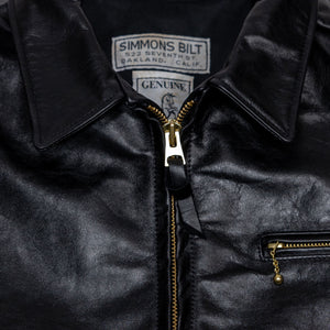 Black leather jacket laid flat on white. Detail of collar & zipper