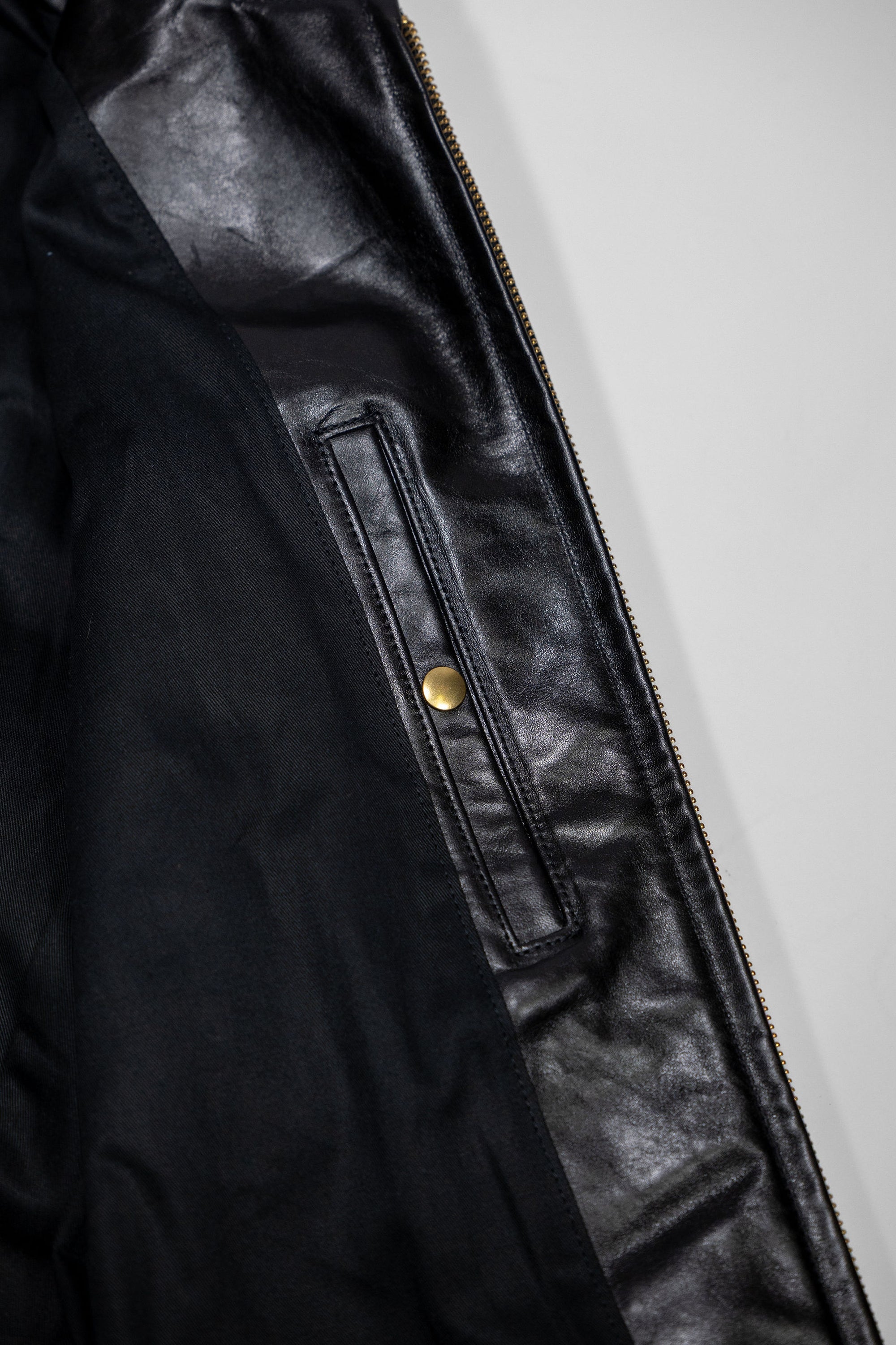 Black leather jacket laid flat on white. Internal chest pocket. 