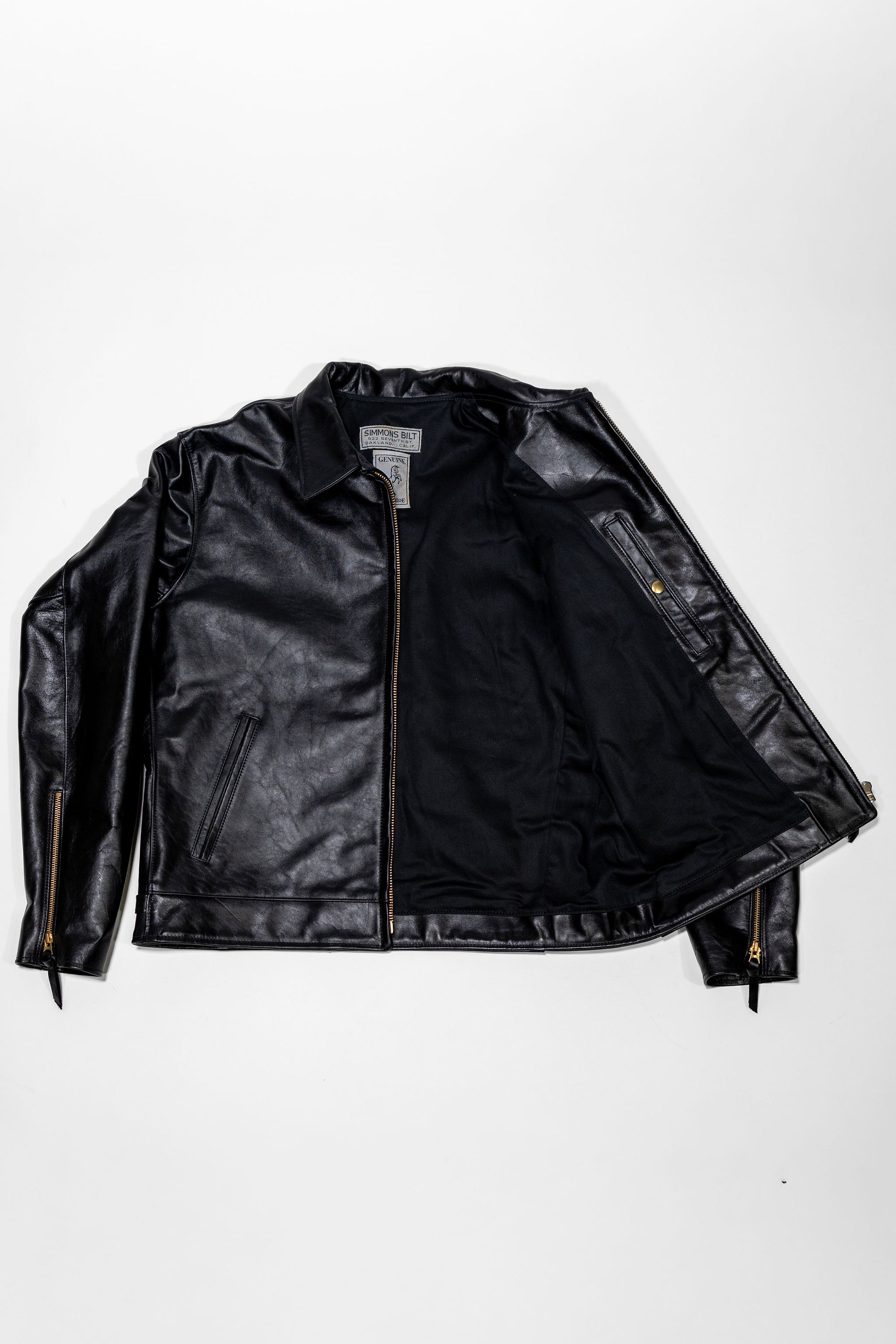 Black leather jacket laid flat on white. Shot from the front unzipped 