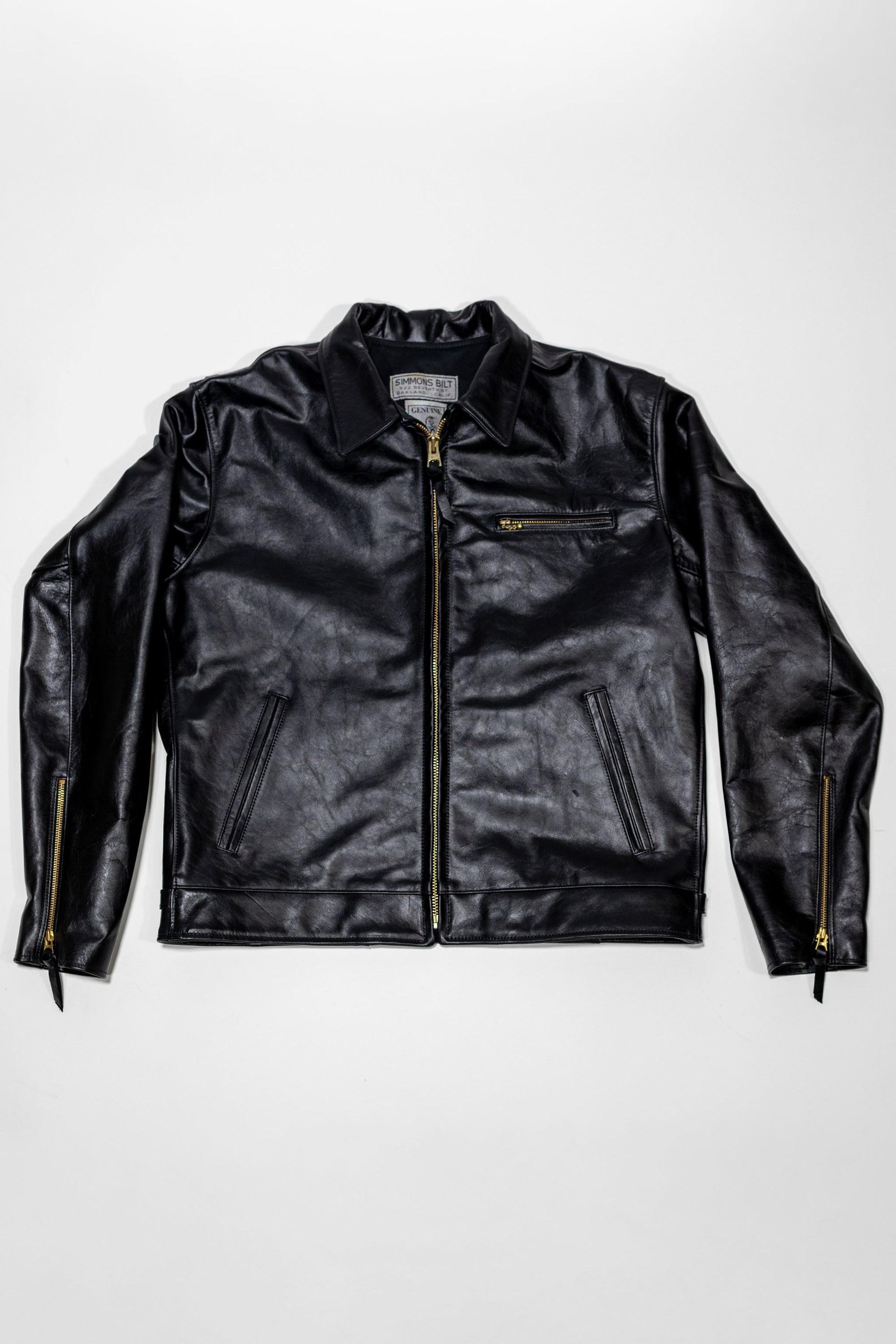 Black leather jacket laid flat on white. Shot from the front.