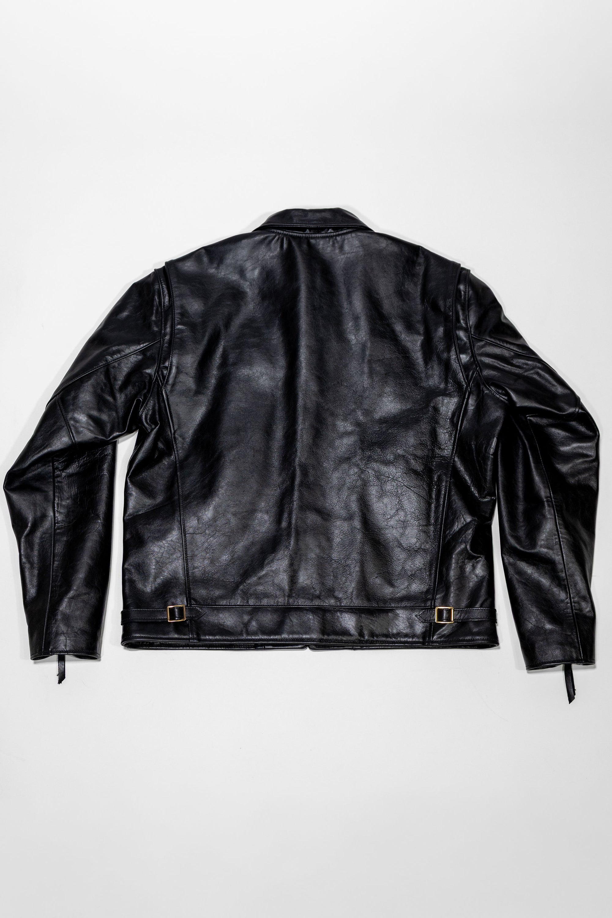 Black leather jacket laid flat on white. Shot from the back.