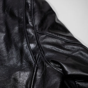 Black leather jacket laid flat on white. Details of sleeve gusset. 