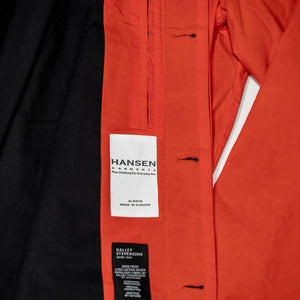 Hansen Garments Morten Long Coat - Waxed Orange laid flat. Details on buttons holes