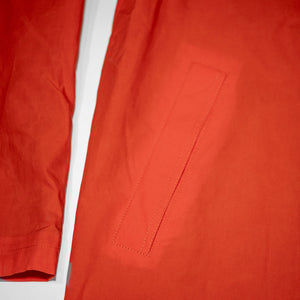 Hansen Garments Morten Long Coat - Waxed Orange laid flat. Details on pocket