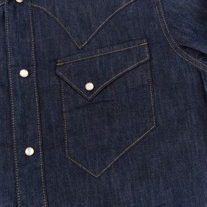 Dark indigo denim western-style shirt with white snaps, close up on left chest pocket laying flat