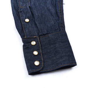 Dark indigo denim western-style shirt with white snaps, close up on sleeve cuff laying flat