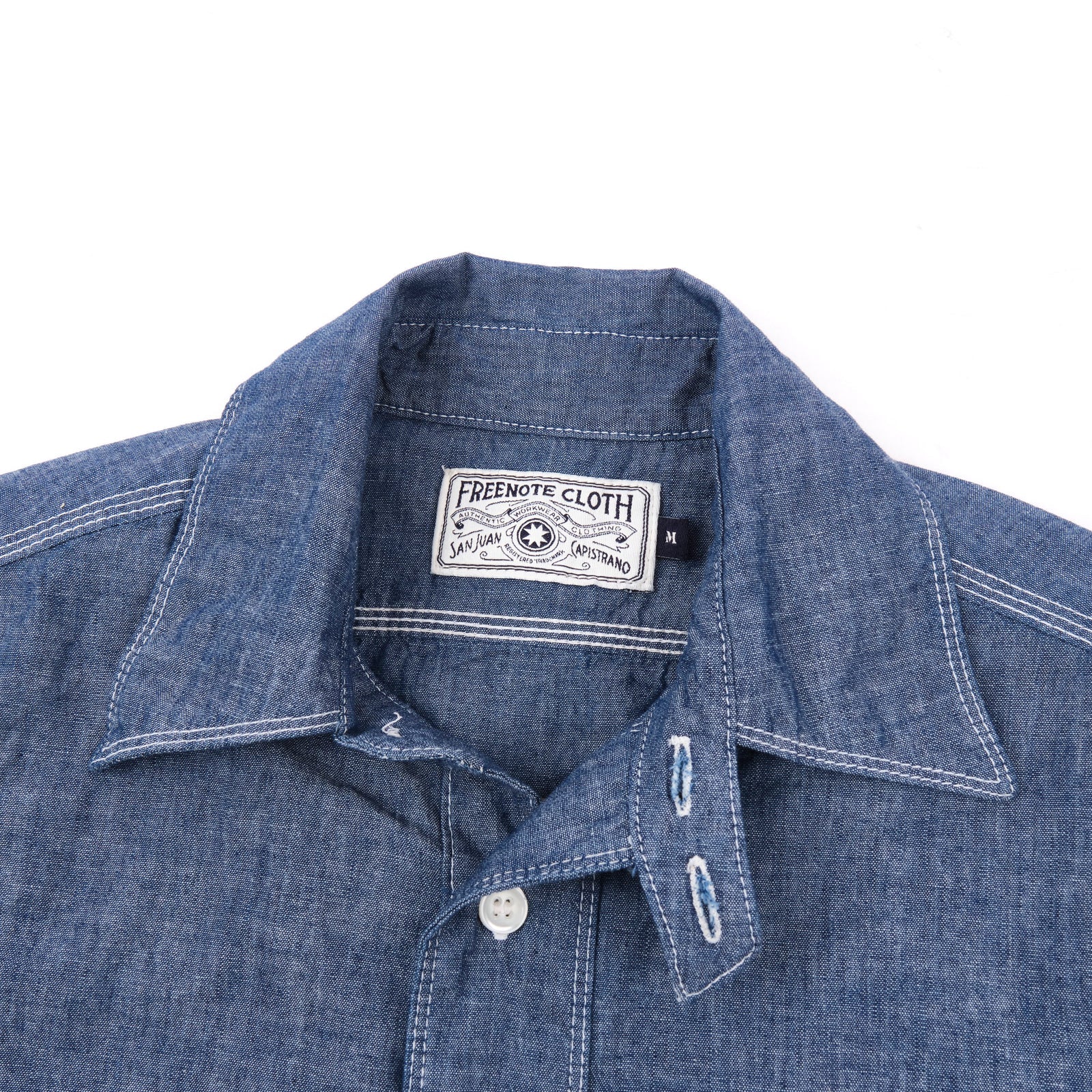 Shirt laid flat on white, from the front. Close up on collar.