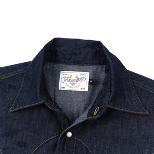 Dark indigo denim western-style short sleeve shirt with white snaps, close up on collar laying flat
